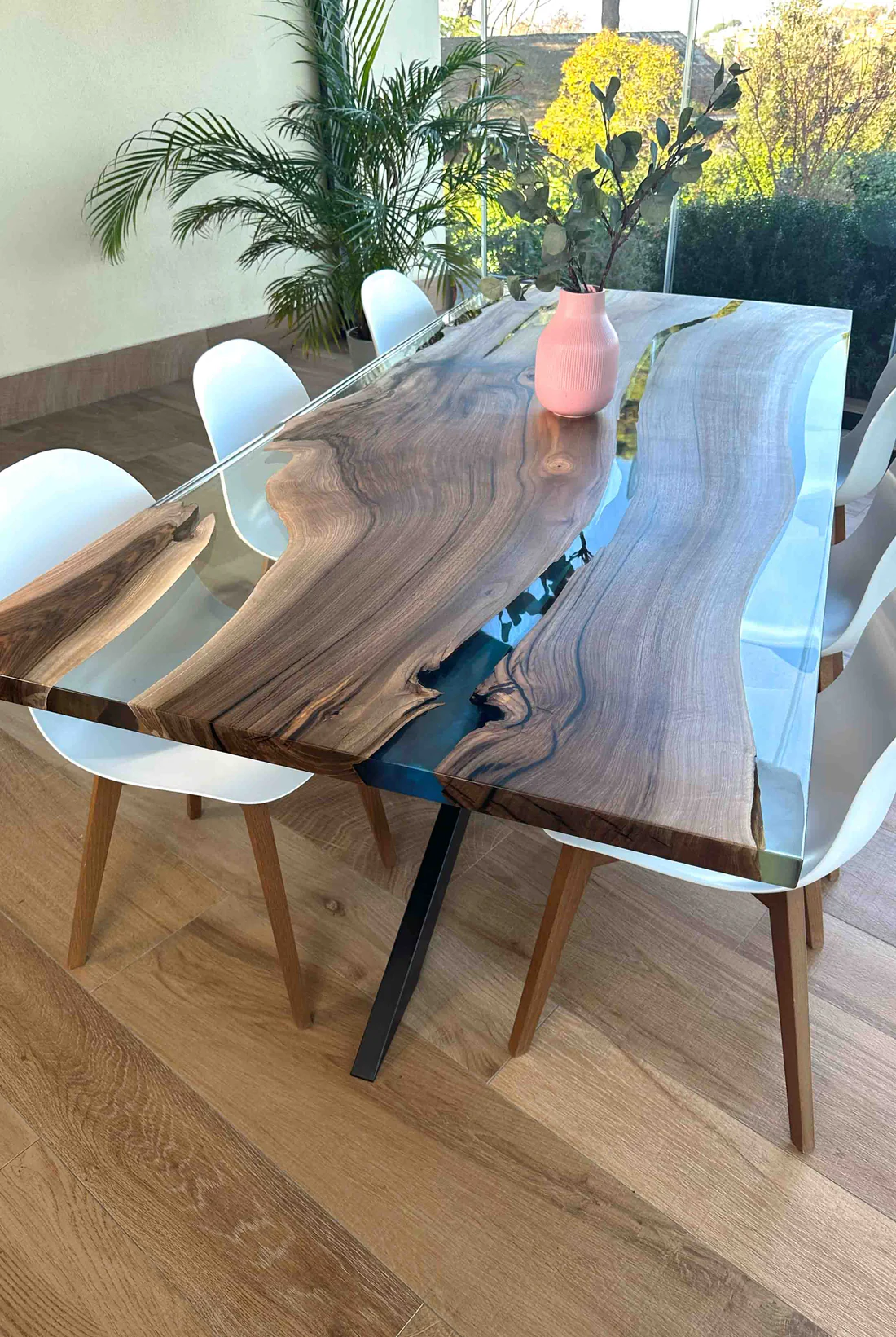 Clear blue walnut epoxy river dining table Armonia with European walnut, glossy clear epoxy resin, pearlescent blue resin river, and matte black cross-shaped metal leg